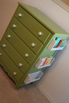 a green dresser with white drawers in the corner next to a wall and carpeted floor