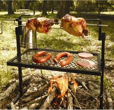 two sausages being cooked on a grill over a campfire in the woods with hot dog buns