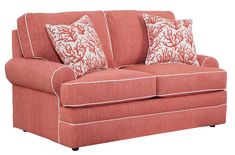 a red couch with pillows on it and white piping around the armrests