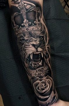 a man's arm with a lion and crown tattoo on it, which has roses in the middle