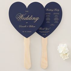 two heart shaped paddles with the names of their wedding guests on them, next to a white flower