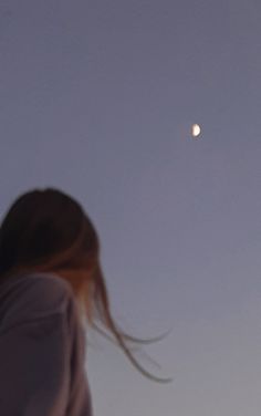 a woman looking up at the moon in the sky