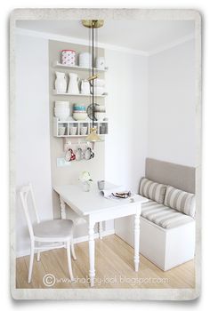 a white table and chairs in a small room with shelves on the wall above it