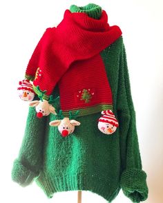 a green sweater with red and white decorations on it