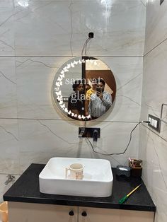 a bathroom with a sink, mirror and light on the wall above it's counter