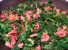 a pan filled with meat and greens on top of a stove