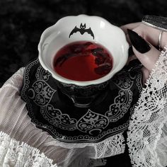 a woman is holding a tea cup with red liquid in it