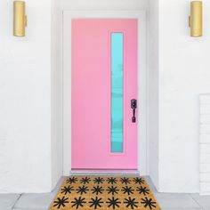 a bright pink door with black flowers on the mat in front of it and two gold doors