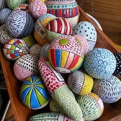 many colorful painted rocks in a wooden box