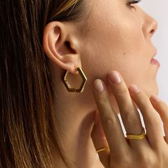 Everyday styling just got easier with our head-turning hexagonal hoop earrings. Handmade in our London studio with recycled brass dipped in 18k recycled gold. Humidity is the enemy; keep it dry! Store your goodies individually in the pouch included with your purchase. Avoid rough wear to slow down the natural process of “wear and tear”. Perfume, hairspray & other types of lotion may contain harsh chemicals that can tarnish your jewellery overtime. For extra care, gently wipe each piece of jewellery clean of any products and skin oils with a soft jewellery polishing cloth. Never use abrasive products to clean your jewellery. They can damage gold plating irreparably. Modern Hexagon Everyday Jewelry, Gold Hexagon Earrings For Everyday, Thick Layers, Modern Jewellery, Forever Jewelry, Jewelry Ring Box, Demi Fine Jewelry, Ring Pendant Necklace, Gold Hoops