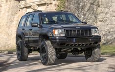 a black jeep parked in front of a stone wall