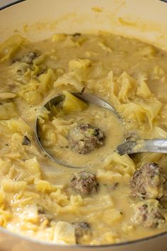 a pot filled with pasta and meatballs on top of a stove next to a spatula