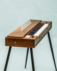 an old wooden piano sitting on top of a black metal stand with a clear acrylic cover over it