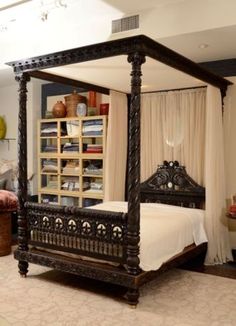 a bedroom with a four poster bed and white curtains