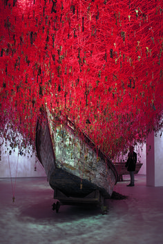 a boat that is sitting in the middle of a room with red strings hanging from it