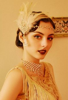 a woman wearing a feathered headpiece and pearls in her hair is posing for the camera