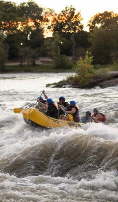 a group of people riding on the back of a raft down a river