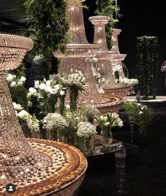 a bunch of vases that are sitting on a table in front of some flowers