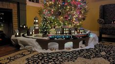 a model train set up in front of a christmas tree with lights on the top