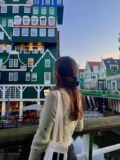 a woman is looking out over the water at some buildings