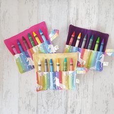 several crayons are lined up in a zippered pouch on a white wooden surface