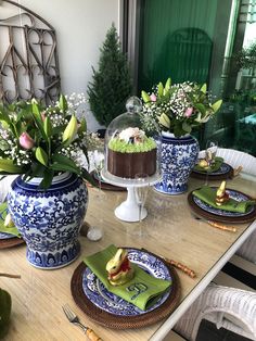 the table is set with blue and white dishes, green napkins, and flowers