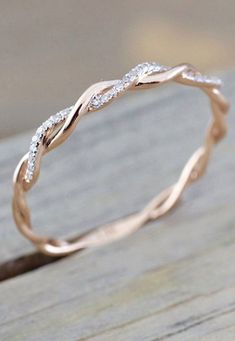 a rose gold wedding band with white diamonds in the center on a wooden surface, ready to be used as a ring