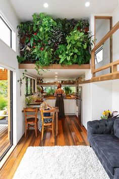 a living room filled with furniture and lots of greenery on the wall above it