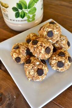 a white plate topped with granola bites next to a jar of yogurt