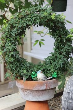 a bird sitting on top of a potted plant in the shape of a wreath