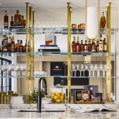 a kitchen with marble counter tops and shelves filled with bottles, glasses, and other items