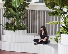 a woman sitting on the ground next to plants