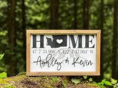 a wooden sign with the words home above it in front of some trees and bushes