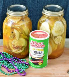 two jars filled with pickles and beads next to a jar of pickles on a table