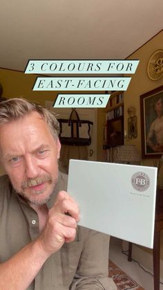 a man holding up a piece of paper with the words 3 colours for east facing rooms