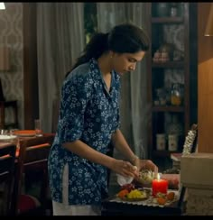 a woman standing in front of a table with food on it and a lit candle