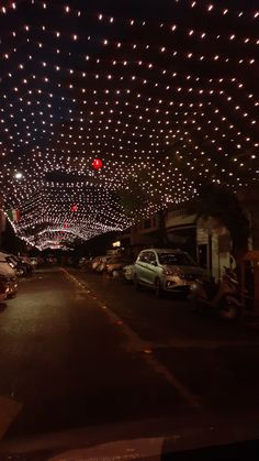 cars are parked on the street in front of many lit up christmas lights and balls