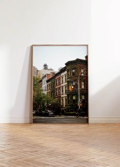 an empty room with a framed photograph on the wall and wood flooring in front of it