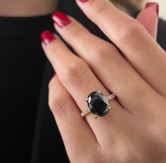 a woman's hand wearing a ring with an oval shaped black diamond on it