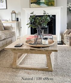 a living room with a couch, coffee table and painting on the fireplace mantel