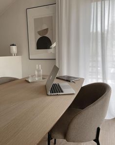 an open laptop computer sitting on top of a wooden table next to a chair in front of a window