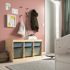 a bedroom with pink walls, white furniture and storage bins on the sideboard