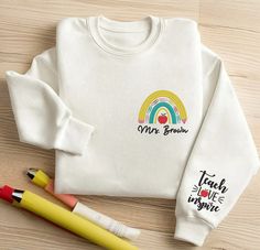 Custom Teacher Embroidered Sweatshirt, Teach Love Inspire Tee, Back To School Gift, Personalized Teacher Name Sweater, Teacher Appreciation 😍 Custom Embroidery: What makes our sweatshirts unique is the custom embroidery feature. Each sweatshirt is adorned with rainbow and customized teacher's name, meticulously stitched to perfection. I T E M ∙ D E T A I L S * Types: Unisex T-Shirt, Sweatshirt, Hoodie * T-shirt material: 100% cotton * Solid colors are 50% cotton and 50% polyester * Sizing: S, M Long Sleeve School Tops With Embroidered Text, Long Sleeve Tops With Embroidered Graphics For School, Name Sweater, Teacher Clothes, Teach Love Inspire, Back To School Gift, Teacher Name, Teacher Outfits, School Gift