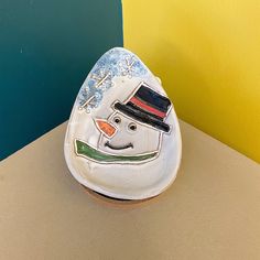 a ceramic snowman with a hat and scarf on it's head sitting on a table