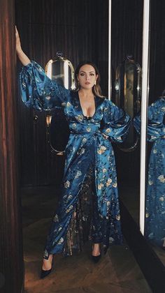 a woman standing in front of a mirror wearing a blue robe and matching heels with her arms outstretched