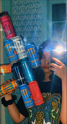 a woman taking a selfie in front of a mirror with many cans on her head