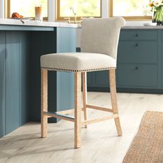 a kitchen with blue cabinets and white counter tops, an area rug and a bar stool in the middle