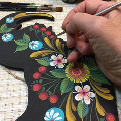 a person is working on a piece of art that looks like a horse head with flowers and leaves painted on it