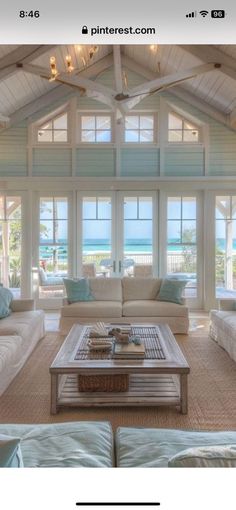 a living room filled with white furniture and windows covered in blue shutters, along with an ocean view