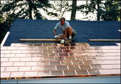 a man working on the roof of a house with shingles and copper colored tiles